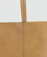 Bolso tipo shopper de tamaño mediano en color camel, con acabado liso y brillante. Cuenta con dos asas de hombro fijas y cierre de botón magnético.