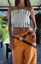 Top strapless de cuero metalizado color dorado, con diseño de tablones verticales en el frente que aportan estructura y elástico en la espalda para un ajuste cómodo.