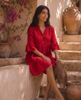 Vestido corto verde militar de lino, con cuello mao, escote en V con botones, mangas tres cuartos acampanadas con volados y falda con volado en el ruedo.