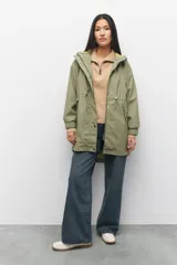 Piloto verde militar de manga larga con capucha y forro de color amarillo. Cuenta con dos bolsillos laterales con solapa, cordones ajustables, elástico en los puños, cierre y botones metálicos.