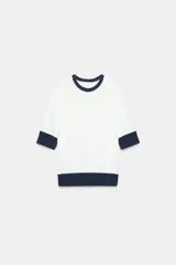 Camiseta de algodón color blanco con cuello redondo, mangas cortas y bajo abullonado, con detalles en color azul marino en el cuello, los puños y el ruedo.