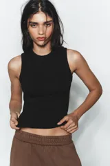 Top musculosa de punto acanalado color blanco, con cuello redondo.