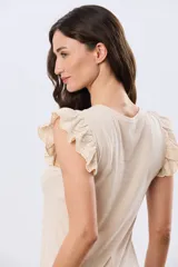 Remera de algodón color beige, de manga corta con volados de broderie, escote redondo y cuerpo liso.