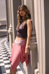 Falda corta con estampado de lunares rojos sobre fondo rosado, con pretina ancha y corte asimétrico con picos.