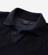 Polo de manga larga color beige claro, confeccionado en tejido texturizado (posiblemente acanalado o waffle). Presenta un cuello polo con escote profundo en V sin botones.