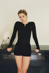 Shorts muy corto de tiro alto, color negro, confeccionado en mezcla de poliamida. Presenta cintura elástica y cierre frontal con cremallera oculta en la costura.