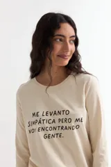 Remera de manga larga color beige con cuello redondo a la base. Presenta un estampado frontal con un dibujo de labios en color fucsia y la palabra 'BESITO' en color negro.