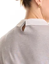 Buzo de punto fino color gris, con cuello camisero de gasa integrado decorado con apliques de perlas y brillos. Presenta mangas largas y puños acanalados.