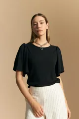 Remera de rib color beige, con cuello redondo y mangas cortas amplias con leve frunce en los hombros. Confeccionada en tejido elastizado de textura acanalada.