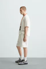 Bermuda de algodón gris con efecto lavado, corte relajado, cintura elástica ajustable con cordón y bolsillos laterales y trasero de vivo.