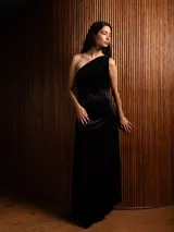 Vestido largo de terciopelo con diseño de un solo hombro y textura plisada. Presenta un corte ajustado en la cintura y una caída fluida hasta el suelo.