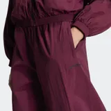 Pantalón deportivo Adidas Originals holgado de color bordó, con cintura elástica, tiro medio y detalles de tres tiras grandes negras en los laterales de las pantorrillas.