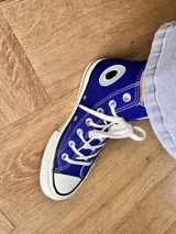 Zapatillas de lona color beige, tipo bota, con cordones marrones, puntera de goma y logo de peach engomado.