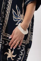 Pulsera rígida de resina translúcida en tono blanco marmolado, de diseño ancho y estilo moderno.