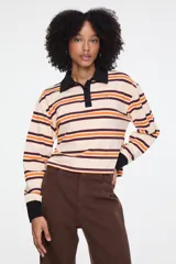 Remera de manga larga con cuello tipo polo, diseño de rayas horizontales y puños en contraste. Su calce relajado y tejido de algodón la convierten en una opción cómoda para el uso diario.