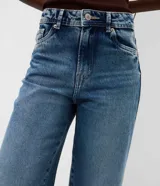 Pantalón wide leg de jean azul con bordado floral aplicado en los laterales. Posee cintura mediana con trabillas, cierre frontal con botón y cremallera, y bolsillos funcionales.