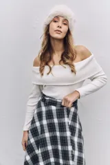 Buzo de punto color blanco, con escote tipo bote que deja los hombros al descubierto y mangas largas ajustadas.