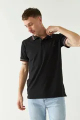 Remera polo negra de manga corta con ajuste regular. Presenta cuello y puños con ribete a rayas en gris y bordó. El logo de la marca está estampado en el pecho.