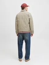 Campera tipo worker de color beige, con cuello camisero, cierre frontal completo y bolsillos laterales. Presenta un diseño minimalista y funcional con acabado limpio.