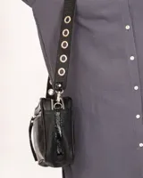 Bandolera negra de charol con doble compartimento, bolsillo frontal, correa regulable con ojalillos y detalles metálicos plateados.