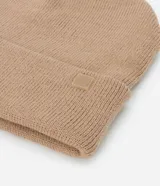 Gorro de punto de estilo beanie, color bordó, con borde plegado y etiqueta decorativa aplicada.