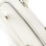 Cartera mini de cuero sintético color blanco, con asas fijas y correa regulable extraíble. Cuenta con cierre superior y placa con el logo de la marca en el frente.