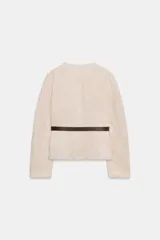 Blazer de cuello redondo y manga larga, confeccionado en tejido efecto ante. Presenta cierre frontal con botones, bolsillos con tapeta en el pecho y cinturón ajustable en la cintura.