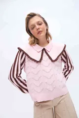 Buzo de punto color rosado con mangas largas a rayas marrones y rosadas. Presenta un doble cuello XL en color rosado con borde marrón y terminación de rulo, además de un cuerpo con detalles de calados y puntos tejidos.