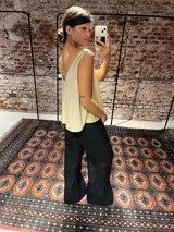 Musculosa dorada de tejido brillante, con escote en V pronunciado en la espalda y diseño holgado.