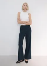 Pantalón azul marino de tiro medio, con bolsillos frontales decorados con botones metálicos dorados y diseño de perneras amplias y rectas.