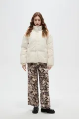 Campera puffer negra con cuello alto, cierre frontal oculto y puños tejidos acanalados. Diseño acolchado con bolsillos laterales.