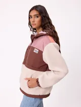 Campera con capucha de diseño combinado en bloques de color. Presenta una sección superior en pana rosada, una franja central en nylon marrón con logo de la marca y cuerpo inferior y mangas en tejido sherpa color crema. Incluye cierre frontal y bolsillos laterales.