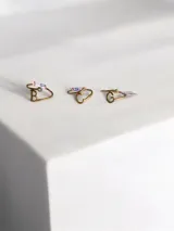 Anillo de metal dorado con diseño de inicial y detalle de pequeña piedra brillante engastada.