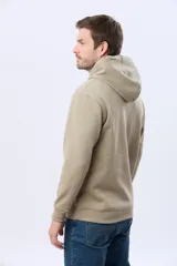 Canguro con capucha y cordones ajustables, confeccionado en felpa lisa color beige, con un pequeño bordado en el pecho.