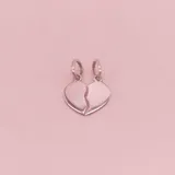Dije de plata 925 con diseño de corazón dividido en dos mitades, cada una con su propia argolla de sujeción.
