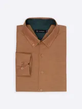 Camisa de manga larga confeccionada en tejido Oxford color marrón. Presenta cuello abotonado, cierre frontal con botones y puños ajustables con doble botón. El interior del cuello cuenta con un detalle en contraste de color verde oscuro.