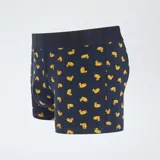 Pack de tres boxers para hombre. Incluye un boxer amarillo liso, un boxer azul marino con estampado de patos amarillos y un boxer azul con estampado de flamencos rosados. Todos tienen cintura elástica con la palabra "ULTIMATE" grabada.