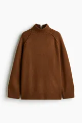 Buzo oversized de punto suave con cuello tortuga acanalado y abertura en la nuca. Presenta mangas raglán con costuras decorativas y terminaciones acanaladas en puños y bajo.