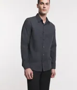 Camisa de manga larga confeccionada en tricolina de algodón, con cuello inglés, cierre frontal de botones y puños abotonados. Diseño liso y versátil.