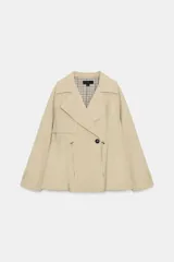 Trench corta de color beige con cuello de solapa y manga larga. Cuenta con bolsillos delanteros, cintura ajustable con cordones, bajo abullonado y cierre frontal cruzado con un botón visible. El interior está forrado con tela a cuadros.