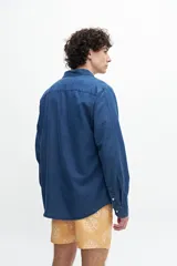 Camisa de denim celeste, manga larga, confeccionada en tela 100% algodón. Tiene un bolsillo en el pecho y botones personalizados.