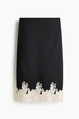 Pollera midi negra de tiro alto, con cintura elástica y detalle de encaje en contraste en el bajo.