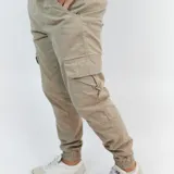 Pantalón cargo color beige de gabardina, con bolsillos laterales y puño en los tobillos.
