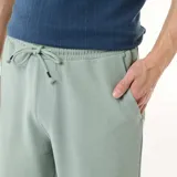 Bermuda de felpa ligera color verde suave, con cintura elástica y bolsillos laterales, de corte cómodo y diseño liso.