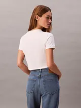 Remera cropped blanca de manga corta y cuello redondo, con logo gráfico de Calvin Klein impreso en el pecho.