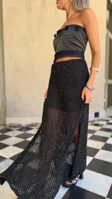 Falda larga negra de tejido red calada con lurex dorado, pretina elástica y tajos laterales. Incluye forro en la zona del caderín.