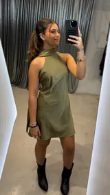Vestido corto de satén color verde oliva, con cuello halter y diseño sin mangas. Presenta un corte fluido y elegante con acabado brillante.