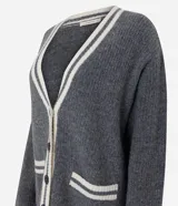 Cardigan de punto gris con escote en V, cierre frontal con botones y detalles de vivos en color crema en el escote, puños, bolsillos y ruedo. Presenta un diseño de corte holgado con mangas largas y bolsillos funcionales.