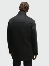 Abrigo corto de paño en color negro, con cierre frontal de botones y cuello alto con pieza interior desmontable con cierre. Presenta un diseño estructurado y elegante.