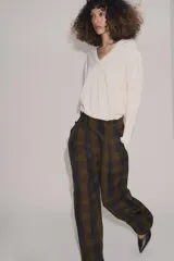Pantalón de tiro alto con diseño fluido y estampado de cuadros en tonos oscuros. Presenta pliegues frontales, bolsillos delanteros con solapa y cierre frontal con cremallera, botón y ganchos metálicos.
